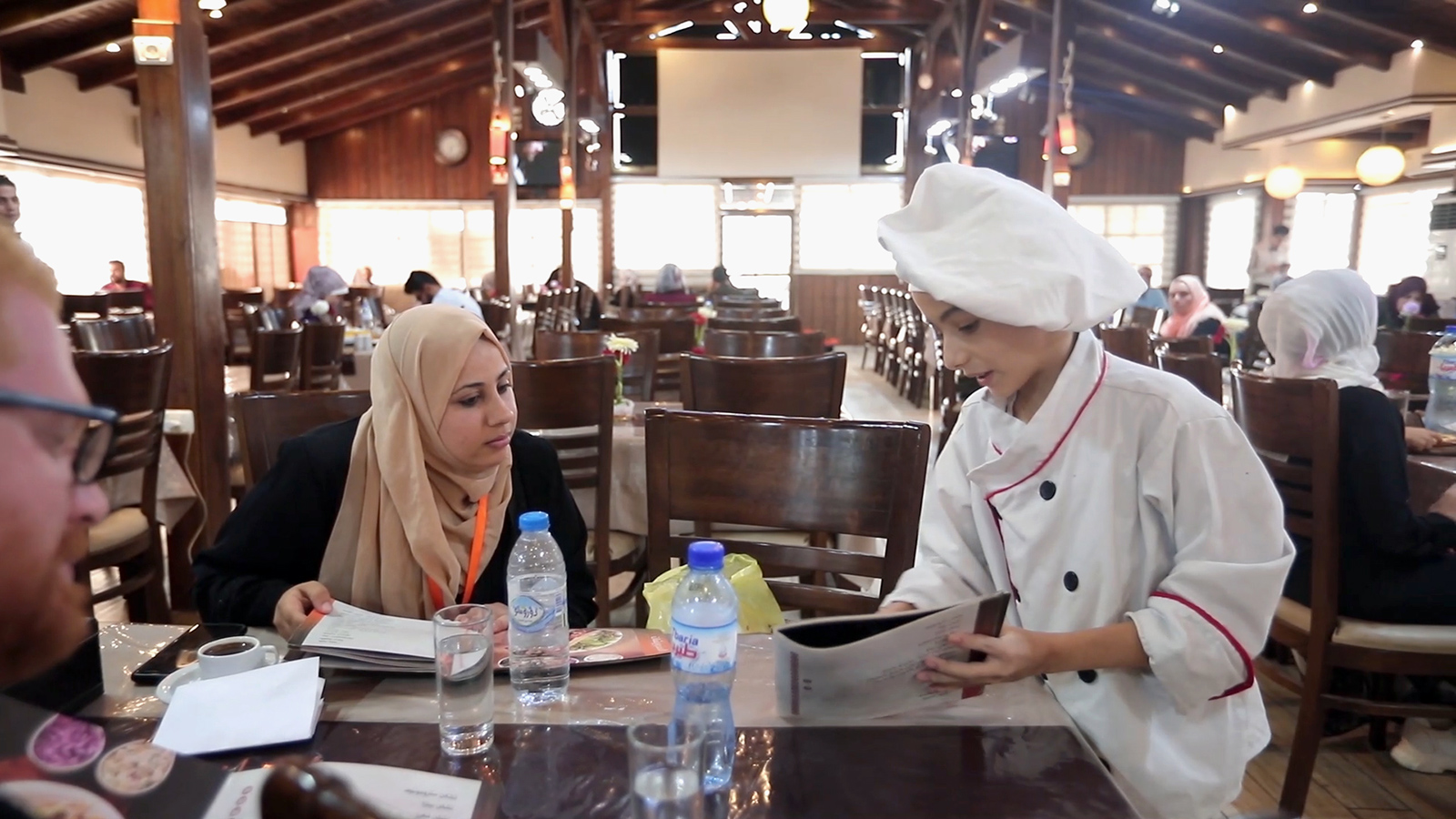 ‪الطفل الشيف يتقن فن تقديم الطعام والتعامل مع الزبائن وجذبهم للأطعمة التي يقدمها المطعم الذي يعمل فيه‬ (الجزيرة)