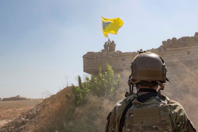 A U.S. soldier oversees members of the Syrian Democratic Forces as they demolish a YPG fortification and raise a Tal Abyad Military Council flag over the outpost as part of the security mechanism zone agreement, in Syria September 21, 2019. Picture taken September 21, 2019. U.S. Army/Staff Sgt. Andrew Goedl/Handout via REUTERS. THIS IMAGE HAS BEEN SUPPLIED BY A THIRD PARTY.