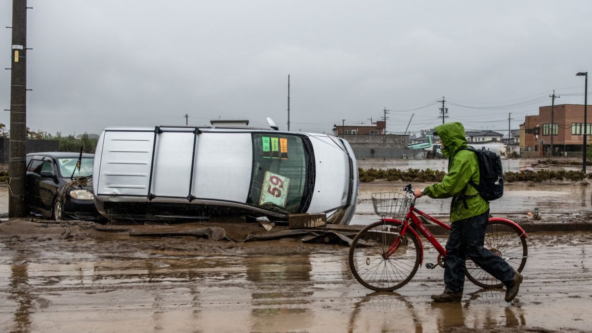 NAGANO, JAPAN - OCTOBER 14: A man pushes his bike past an upturned car in a road that was flooded during Typhoon Hagibis, on October 14, 2019 in Nagano, Japan. Japan has mobilised 110,000 rescuer workers after Typhoon Hagibis, the most powerful storm in decades, swept across the country leaving 37 dead and around 20 missing. (Photo by Carl Court/Getty Images)