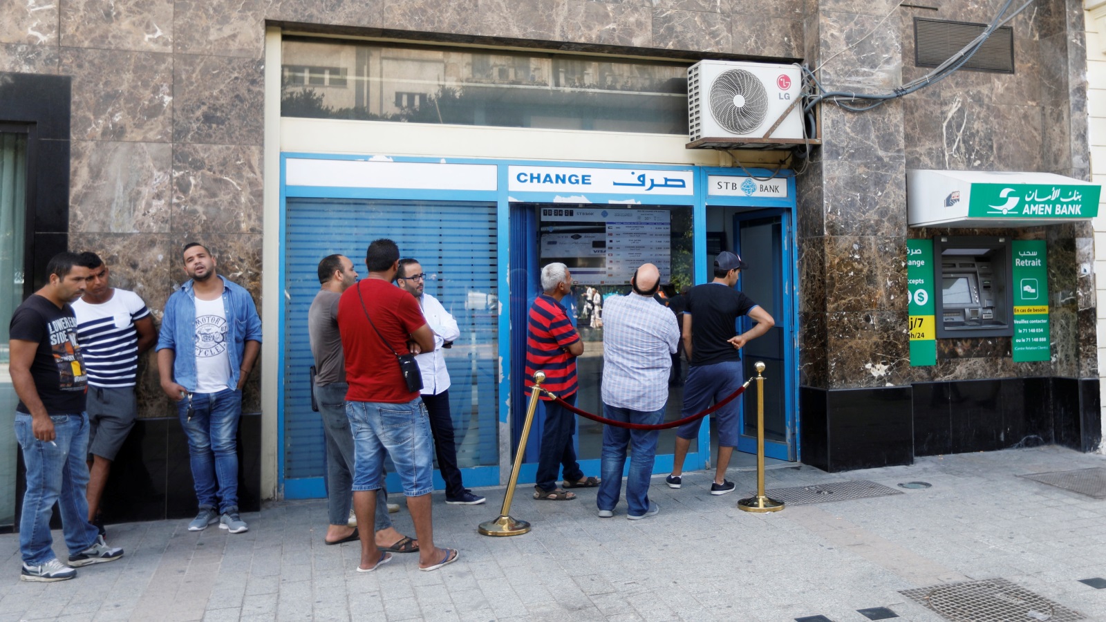 ‪تونسيون يقفون في طابور أمام محل لصرف العملات‬ (رويترز)