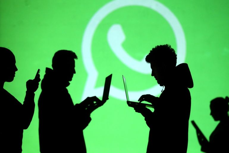 Silhouettes of laptop and mobile device users are seen next to a screen projection of Whatsapp logo in this picture illustration taken March 28, 2018. REUTERS/Dado Ruvic/Illustration
