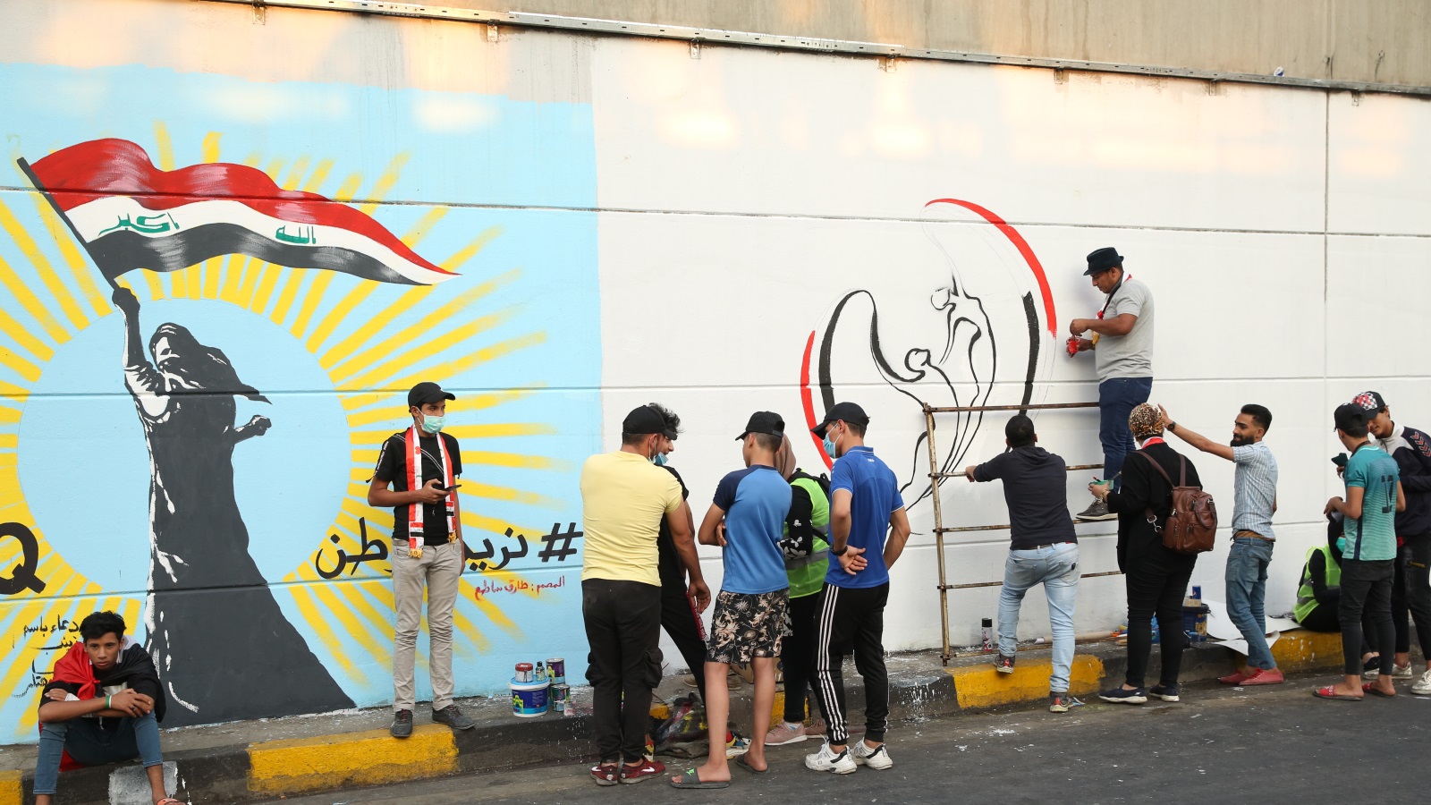 محتجون يعبرون عن مواقفهم خلال جداريات وسط بغداد (الأناضول)