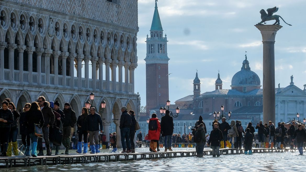 People walk through across a makeshift walkway over the flooded St. Mark's Square in Venice
