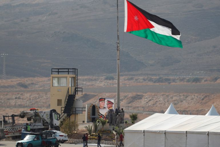 A Jordanian national flag is lifted near a tent at the