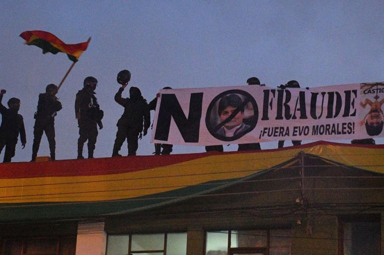 epa07982480 Bolivian police officers display a billboard that reads: 'No fraud. Out Evo Morales' from the roof of a police station in Cochabamba, Bolivia, 08 November 2019. A group of Bolivian police took control of a police station in protest against Bolivian President Evo Morales. Bolivia is immersed in a political crisis stemming from accusations by opposition and civic organizations that longtime incumbent President Evo Morales' latest election victory was tainted by fraud. EPA-EFE/Jorge Abrego