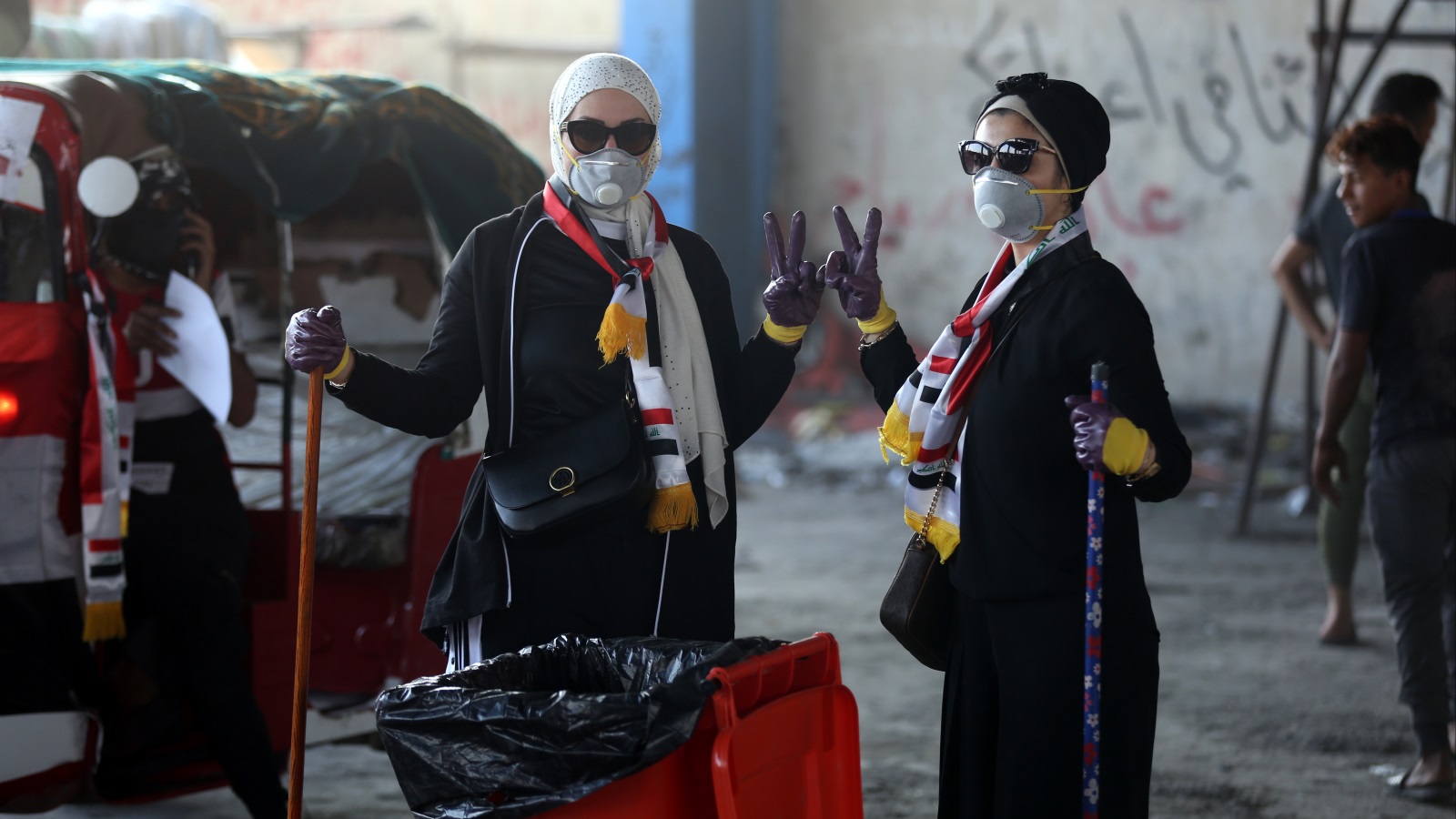فتاتان تنظفان المكان قرب ساحة التحرير في بغداد دعما للمظاهرات (الأناضول)