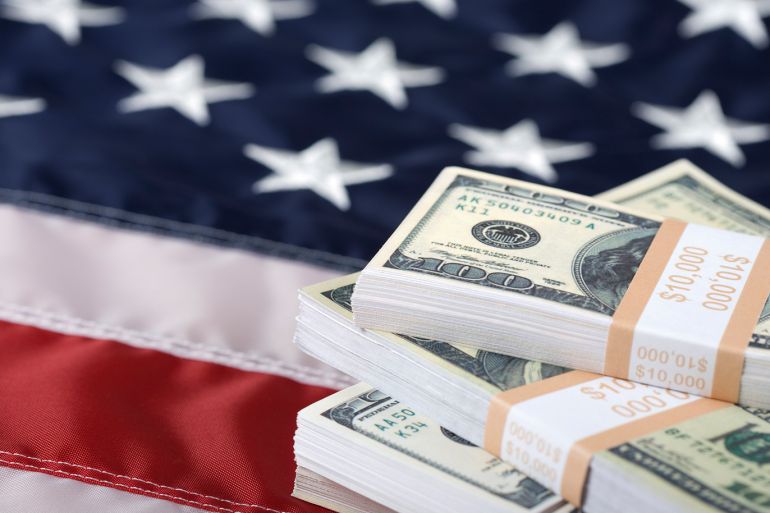 Macro shot of bundles of new $100 bills on US flag. Selective focus on the money.