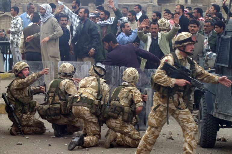 British Army troops take position near a crowd of protesting former Iraqi soldiers after stones were thrown in the southern Iraq city of Basra January 6, 2004. Picture taken January 6, 2004. REUTERS/Atef Hassan/File Photo