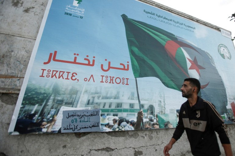 A man walks past a campaign poster for presidential election in Algiers, Algeria November 2, 2019. The poster reads: