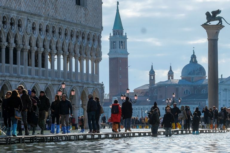 People walk through across a makeshift walkway over the flooded St. Mark's Square in Venice