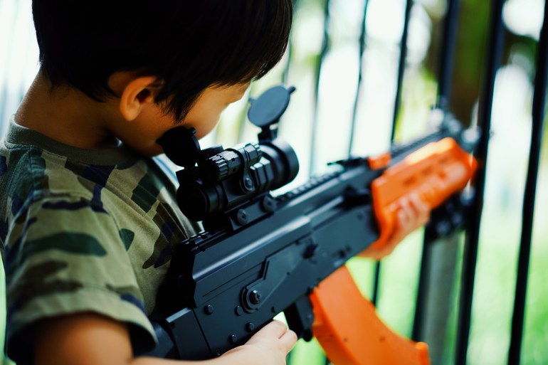 Side View Of Boy Playing With Toy Gun