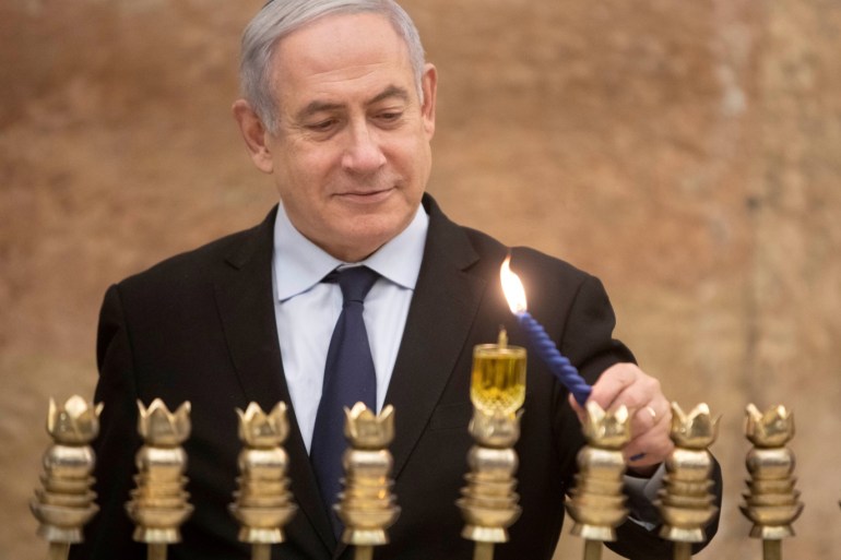 Israeli Prime Minister Benjamin Netanyahu, lights a Hanukkah candle at the Western Wall, the holiest site where Jews can pray in Jerusalem's old city, December 22, 2019. Sebastian Scheiner/Pool via REUTERS