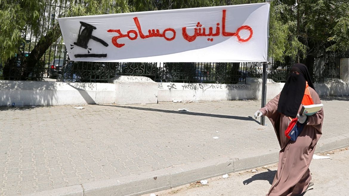 A veiled woman walks past a sign during a demonstration against a bill that would protect from prosecution those accused of corruption, in front Assembly of People's Representatives headquarters in Tunis, Tunisia July 28, 2017. The sign reads