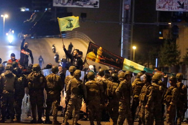 Supporters of the Lebanese Shi'ite groups Hezbollah and Amal carry flags as Lebanese army soldiers are deployed in Beirut, Lebanon, November 25, 2019. REUTERS/Mohamed Azakir