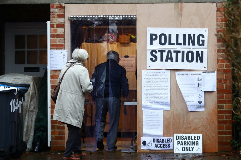Two elders enter the garage of a residential house, converted to a poling station, to vote in the general election in South Croydon, in London, Britain, December 12, 2019. REUTERS/Hannah McKay