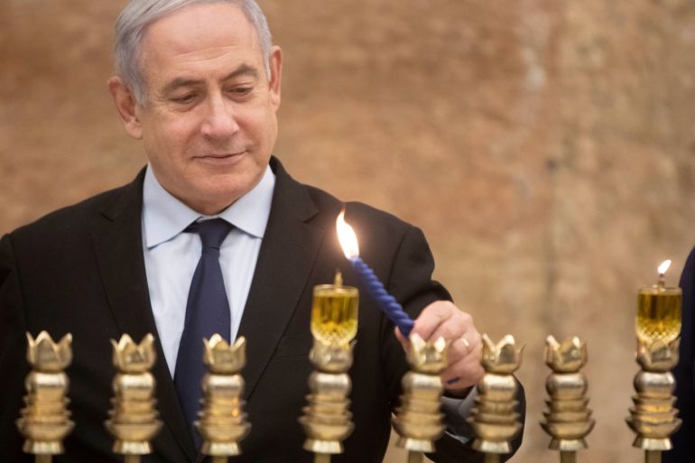 Israeli Prime Minister Benjamin Netanyahu, lights a Hanukkah candle at the Western Wall, the holiest site where Jews can pray in Jerusalem's old city, December 22, 2019. Sebastian Scheiner/Pool via REUTERS
