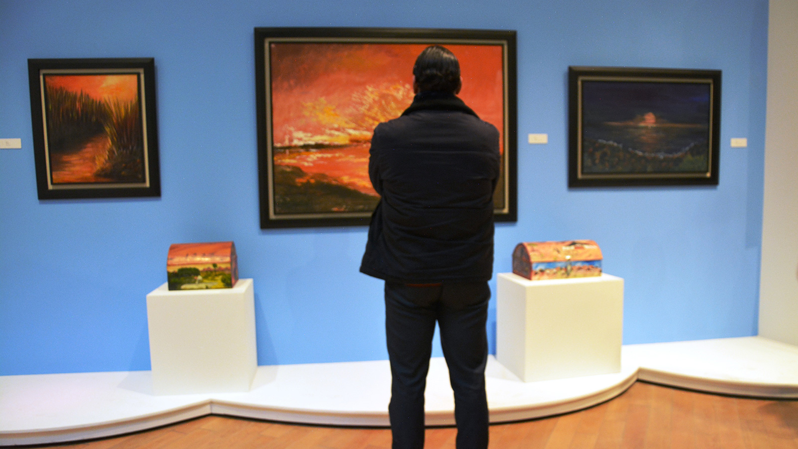 ‪واحد من جمهور المعرض يقف قبالة إحدى اللوحات التي تجسد لحظات الاحتراق الداخلي‬ (الجزيرة)
