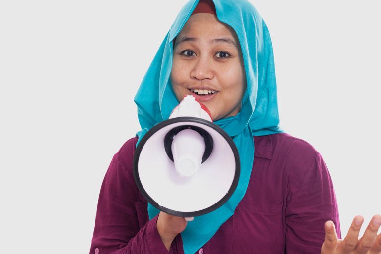 Portrait of Asian muslim woman calling or offering something with megaphone isolated on white, advertising marketing concept