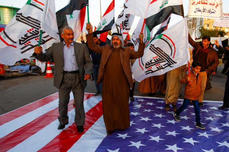 Iraqi people walk on a U.S. flag in a protest after an airstrike at the headquarters of Kataib Hezbollah militia group in Qaim, in the holy city of Najaf, Iraq December 30, 2019. REUTERS/Alaa al-Marjani
