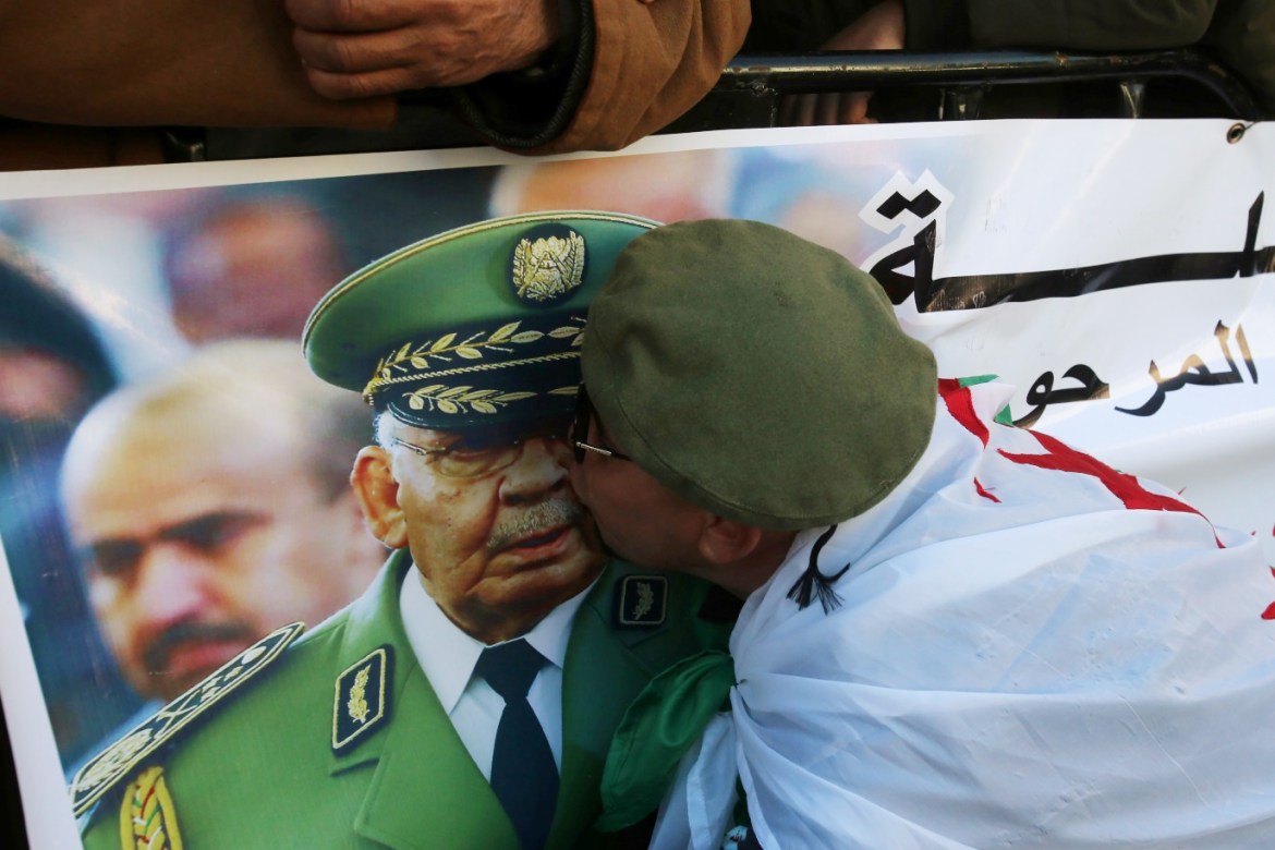 A participant kisses the image of Lieutenant General Ahmed Gaed Salah on a banner as people gather outside the Palace of the People during the funeral of the late Algeria's military chief in Algiers, Algeria December 25, 2019. REUTERS/Ramzi Boudina
