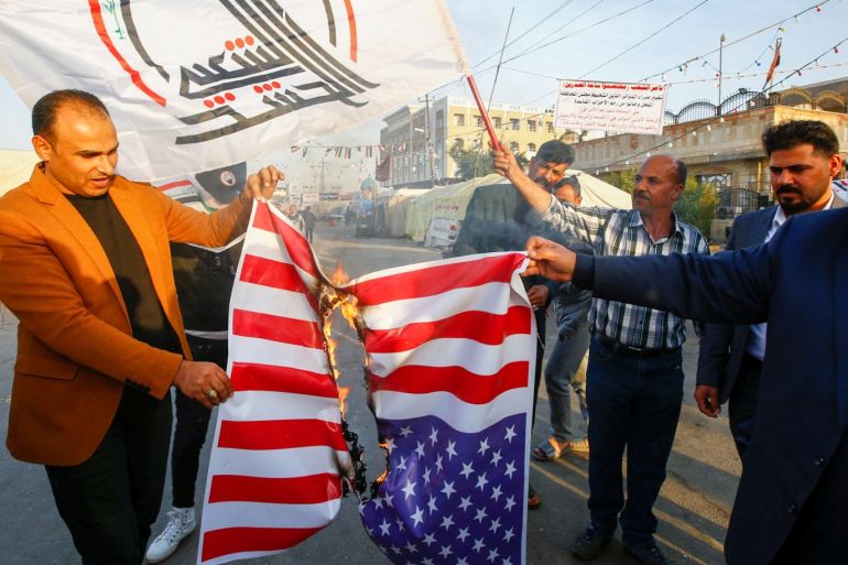Iraqi people burn a U.S. flag in a protest after an airstrike at the headquarters of Kataib Hezbollah militia group in Qaim, in the holy city of Najaf, Iraq December 30, 2019. REUTERS/Alaa al-Marjani