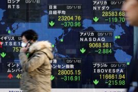 People walk past an electronic display showing world markets indices outside a brokerage in Tokyo, Japan, January 8, 2020. REUTERS/Issei Kato