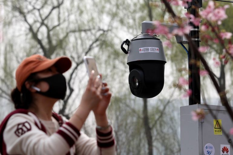 A high-resolution AI camera with 5G network provided by Huawei and China Mobile is seen near a visitor holding her mobile phone under blooming cherry blossoms, at Yuyuantan park in Beijing, China March 19, 2019. Picture taken March 19, 2019. REUTERS/Stringer ATTENTION EDITORS - THIS IMAGE WAS PROVIDED BY A THIRD PARTY. CHINA OUT. NO COMMERCIAL OR EDITORIAL SALES IN CHINA.