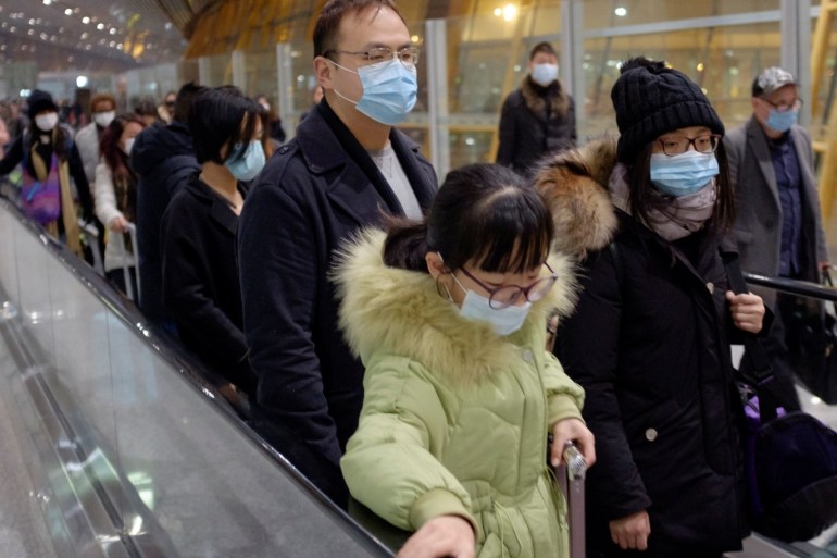 People wear face masks as they arrive at Beijing Capital International Airport in Beijing, January 25, 2020. REUTERS/Thomas Peter