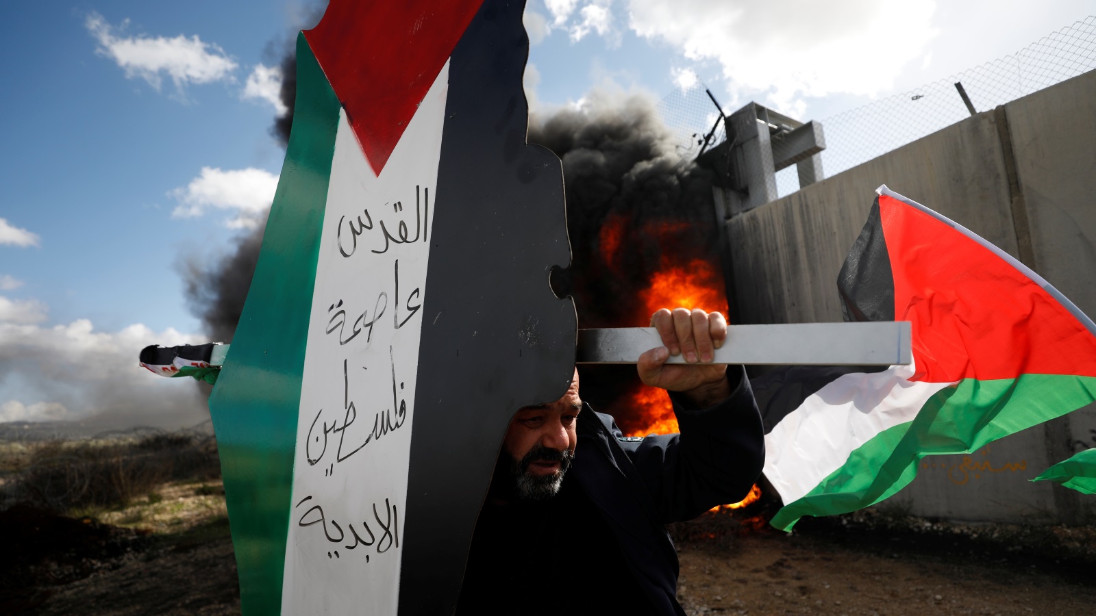 ‪فلسطيني يحمل لافتة تعبر عن التمسك بالقدس قرب جدار الفصل ببلدة بلعين في الضفة الغربية‬ (رويترز)