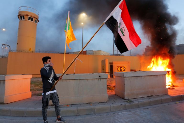 A protester holds an Iraqi flag during a protest to condemn air strikes on bases belonging to Hashd al-Shaabi (paramilitary forces), outside the main gate of the U.S. Embassy in Baghdad, Iraq December 31, 2019. REUTERS/Wissm al-Okili