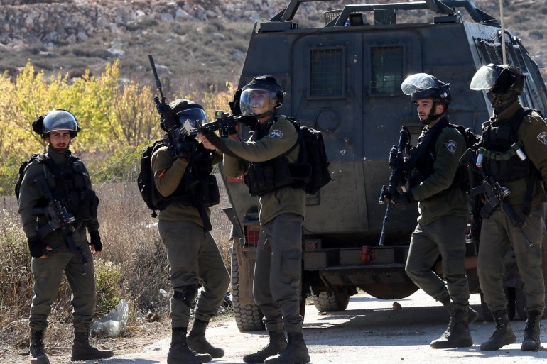 epa08008296 An Israeli border policeman aims his weapon during a protest against the demolition of under-construction Palestinian houses by Israeli forces near Arroub refugee camp north of the West Bank city of Hebron, 19 November 2019. Israel on a regular basis demolishes Palestinians' houses in the West Bank citing missing building permits for Area C. EPA-EFE/ABED AL HASHLAMOUN