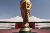 كأس العالم وفي خلفيته ملعب البيت الذي سيستضيف مباراة افتتاح مونديال قطر (الجزيرة)