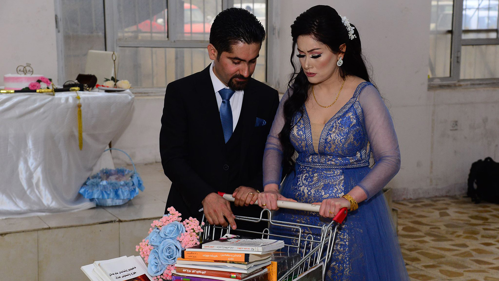 العروسان خلال حفل زفافهما وزعا الكتب على المدعوين (الجزيرة)