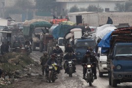 Men riding on motorbikes pass the trucks that carry belongings of displaced Syrians, in northern Idlib, Syria January 30, 2020. Picture taken January 30, 2020. REUTERS/Khalil Ashawi
