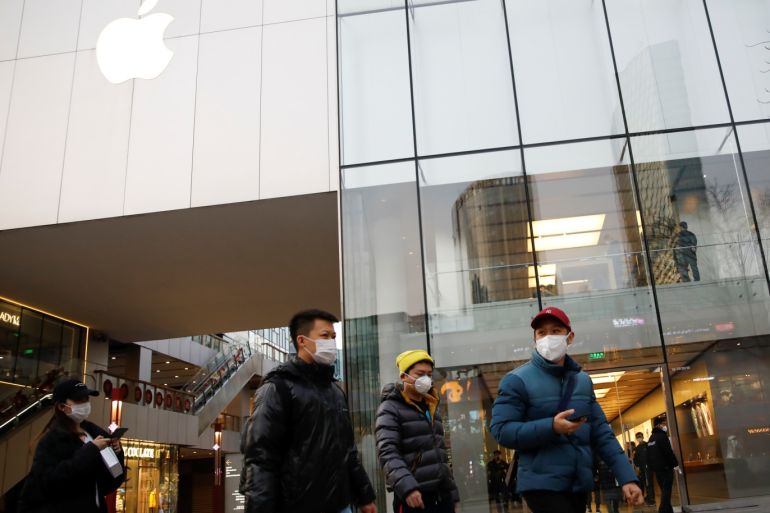 People wearing face masks walk in front of an Apple store at a shopping mall, as the country is hit by an outbreak of the new coronavirus, in Beijing, China February 18, 2020. REUTERS/Carlos Garcia Rawlins
