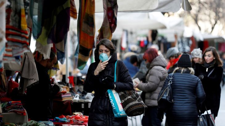 A woman wearing a protective face mask walks through a street market, as a coronavirus outbreak continues to grow in northern Italy, in Milan, Italy, February 27, 2020. REUTERS/Yara Nardi