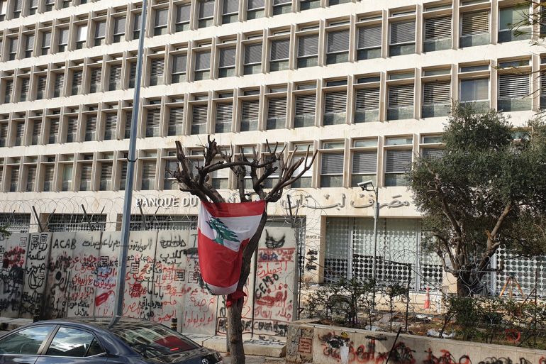 مصرف لبنان الداعم لمؤسسة الإسكان وتبدو شعارات الثورة على الحيطان الموضوعة حديثا لحمايته- الجزيرة.