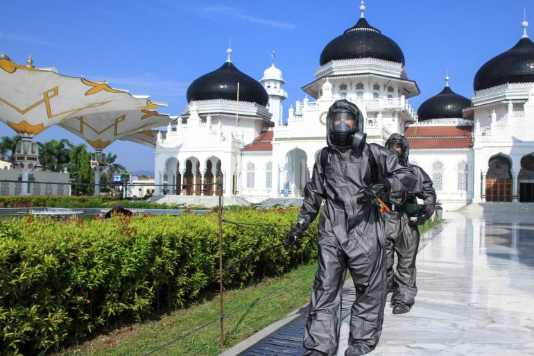 Precaution coronavirus in Aceh, Indonesia- - ACEH, INDONESIA - MARCH 21: Aceh police personnel with protective suit spray disinfectant as a part prevention spread coronavirus (COVID-19) at Baiturrahman Mosque, in Aceh, Indonesia on March 21, 2020.