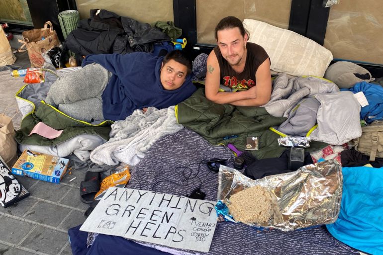Ross Standley, 23, and James Sears, 27, sit outside an under construction restaurant in Berkeley, California March 20, 2020. The homeless individuals have seen their income from panhandling significant decrease in the last week as the coronavirus disease (COVID-19) outbreak has emptied streets in the university town. REUTERS/Paresh Dave