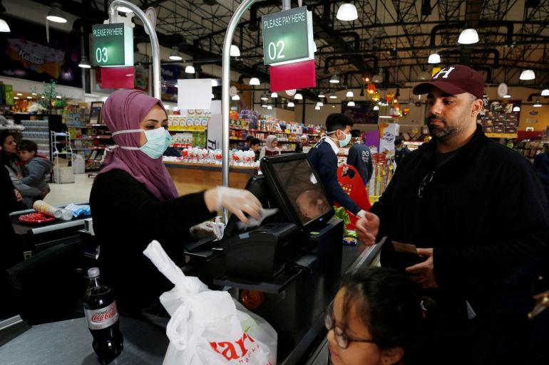 A Palestinian cashier, wearing a mask amid coronavirus precautions, deals with a customer in a supermarket in Gaza City March 8, 2020. Picture taken March 8, 2020. REUTERS/Mohammed Salem