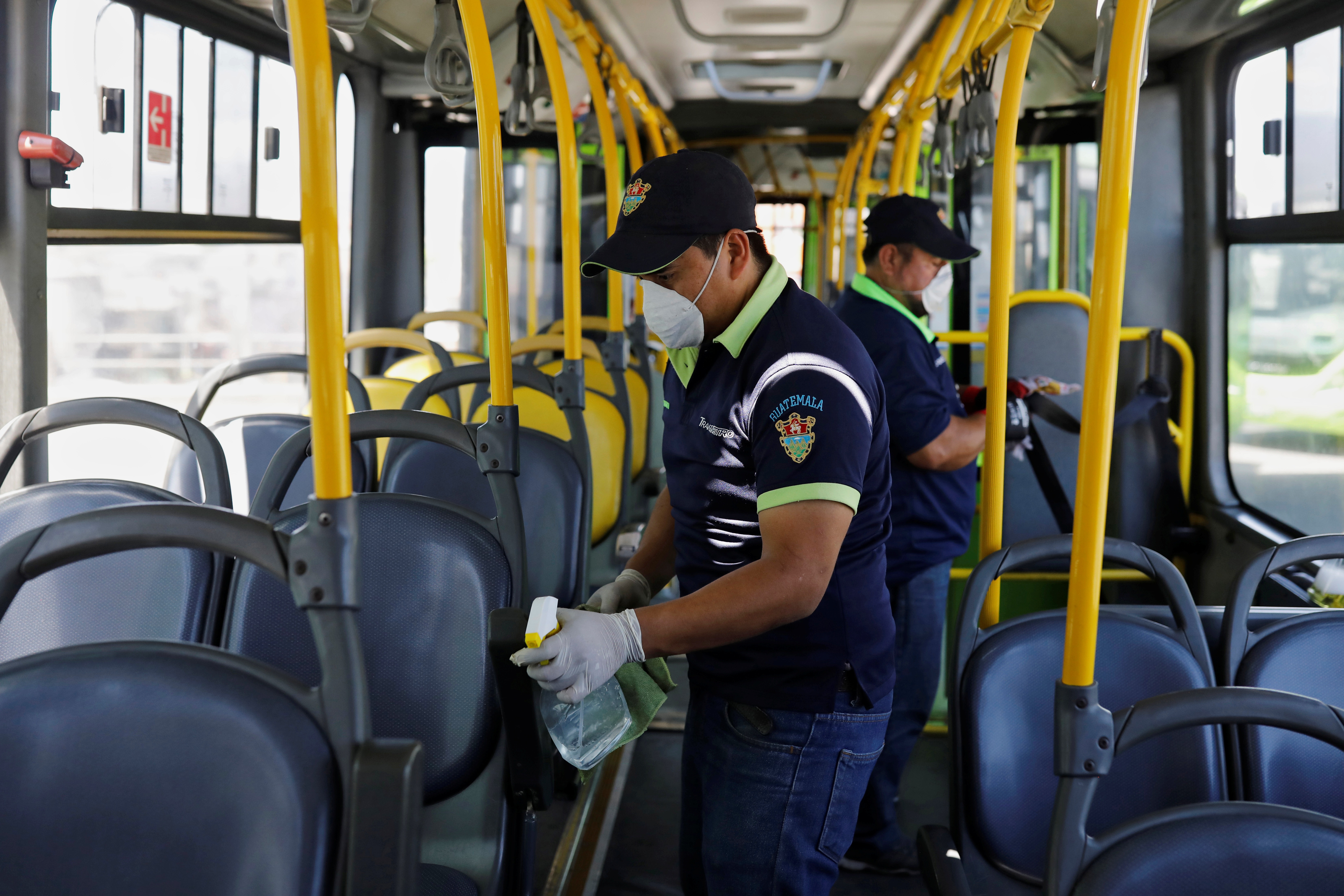 عمال يرتدون أقنعة واقية ينظفون الجزء الداخلي من حافلة عامة وسط مخاوف من انتشار مرض فيروس كورونا المستجد (رويترز)