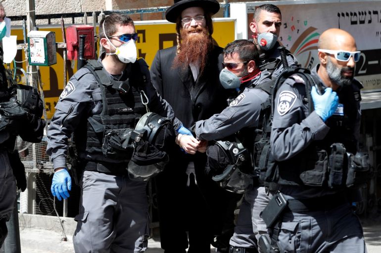 Israeli policemen detain an ultra-Orthodox Jewish man as they enforce government restrictions to fight the spread of the coronavirus disease (COVID-19) after Israeli Prime Minister Benjamin Netanyahu last week tightened a national stay-at-home policy, saying police would enforce restrictions, in the ultra-Orthodox Jewish neighborhood of Mea Shearim in Jerusalem March 24, 2020. REUTERS/Ronen Zvulun