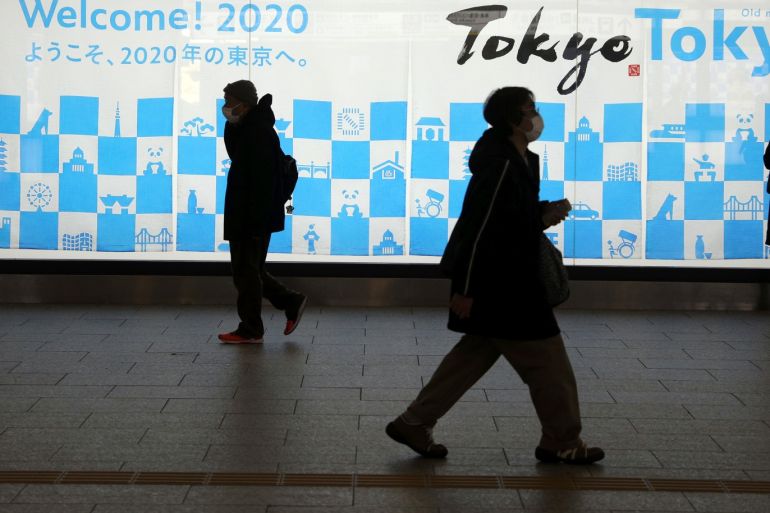 A man wearing a protective mask, following an outbreak of the coronavirus disease (COVID-19), walks in front of an advertising billboard of Tokyo Olympics 2020, near the Shinjuku station in Tokyo, Japan, March 15, 2020. REUTERS/Stoyan Nenov