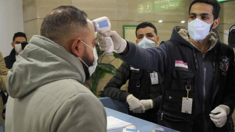 أطباء يجرون فحص كورونا على المسافرين في مطار القاهرة (الفرنسية)