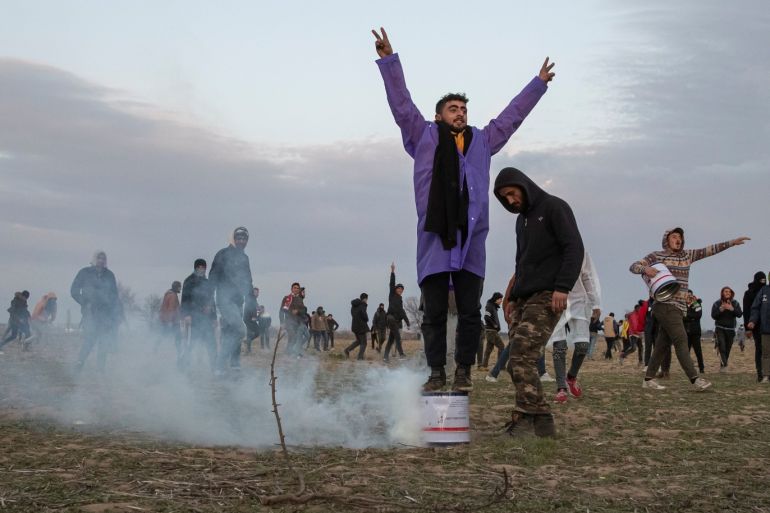 A migrant reacts while others stand near a cloud of tear gas as they gather on the Turkish-Greek border near Turkey's Pazarkule border crossing with Greece's Kastanies, in Edirne, Turkey March 7, 2020. REUTERS/Marko Djurica