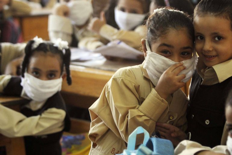 Schoolgirls wearing face masks pose for the camera in a classroom in Cairo October 4, 2009. The Egyptian government delayed the opening of state-run and many private schools because of the Muslim fasting month of Ramadan and concerns over the spread of the H1N1 virus. Local media reported that schools will make a shift to distance learning to prevent the spread of the H1N1 virus. REUTERS/Stringer (EGYPT EDUCATION HEALTH)