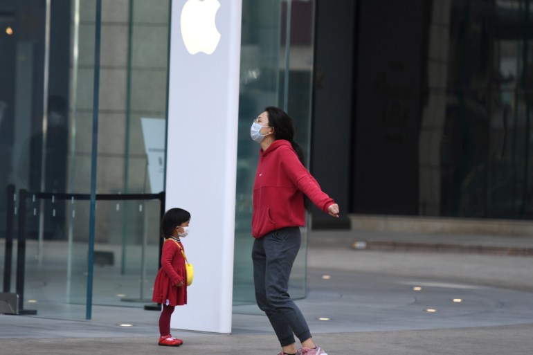 People wear face masks in front of an Apple Store, as the country is hit by an outbreak of the novel coronavirus, in Kunming, Yunnan province, China February 23, 2020. REUTERS/Stringer CHINA OUT.