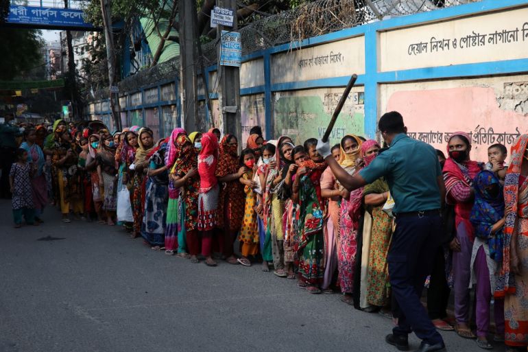 A policeman wields his baton as he tells to people to stay in the queue in order to receive relief supplies provided by local community amid the coronavirus disease (COVID-19) outbreak in Dhaka, Bangladesh, April 1, 2020. REUTERS/Mohammad Ponir Hossain