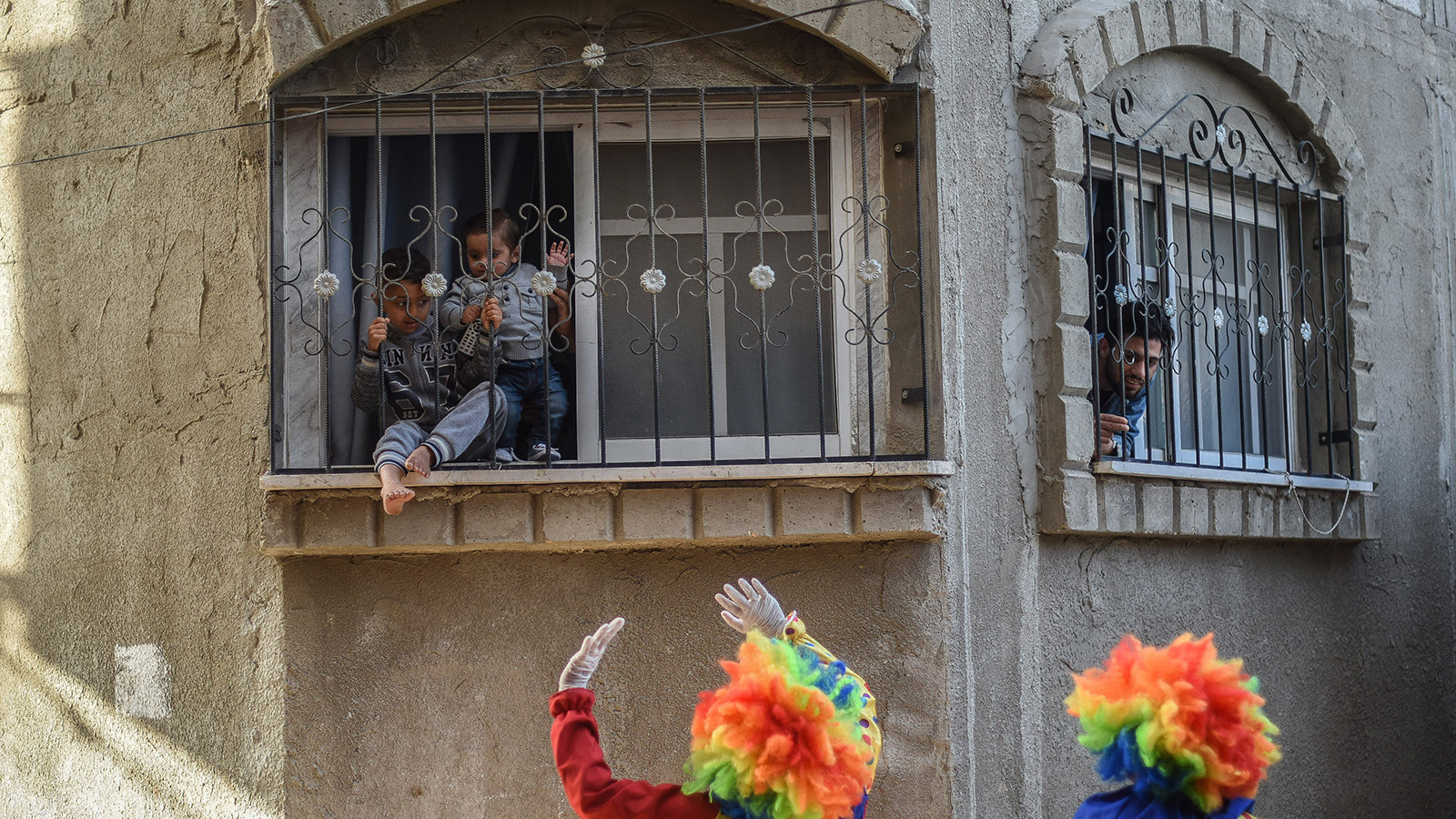 ‪الأطفال يطلون من النوافذ لمتابعة عروض المهرجين‬ (الجزيرة)