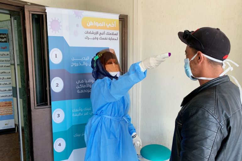 A nurse checks the temperature of a man before he enters a medical clinic, following the outbreak of the coronavirus disease (COVID-19), in Misrata, Libya March 31, 2020. Picture taken March 31, 2020. REUTERS/Ayman Al-Sahili